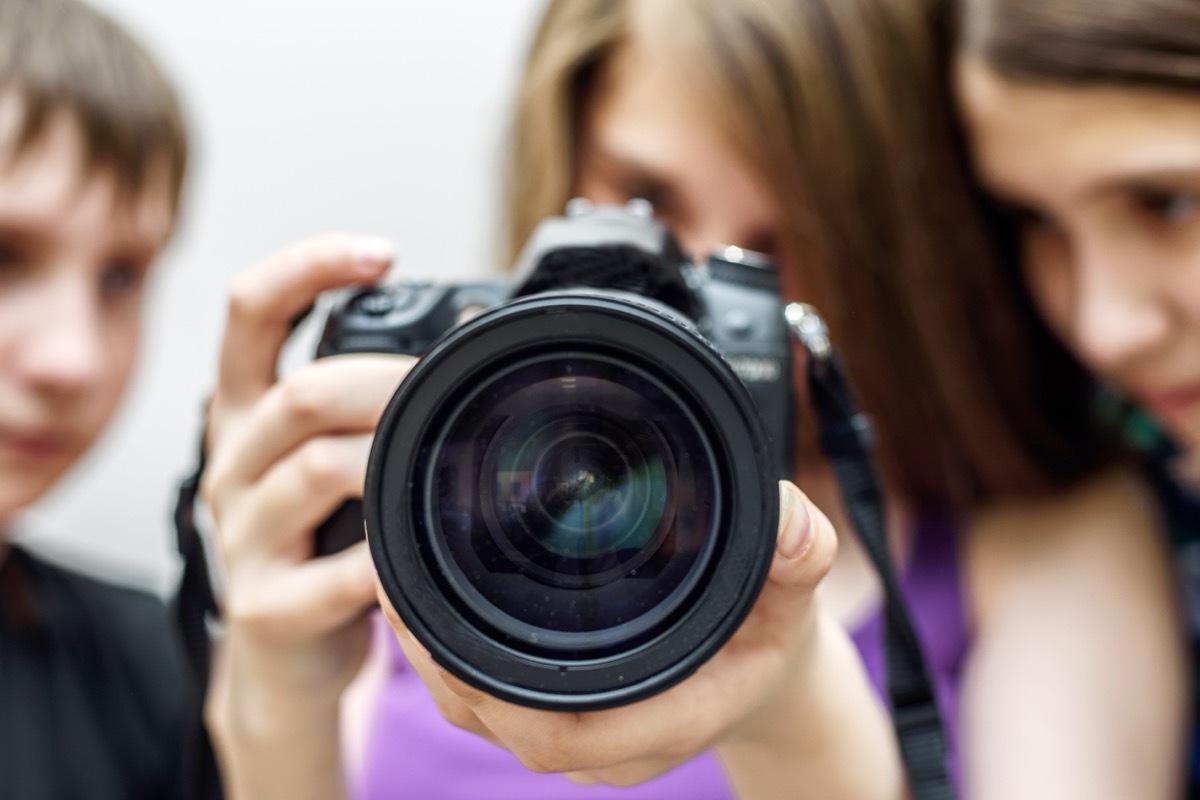 Drei Jugendliche fotografieren gemeinsam mit einer Spiegelreflexkamera