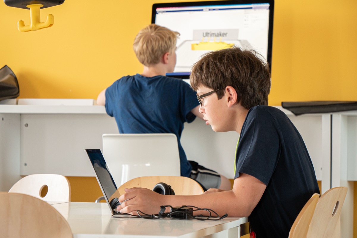 Zwei Jungen programmieren an Laptops in einem hellen Raum